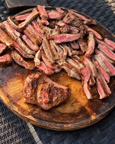 Sliced grilled beef on a wooden serving board