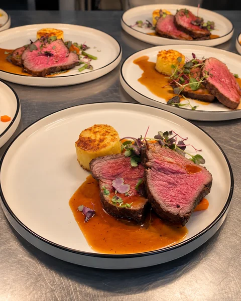Beef and vegetables arranged on white plates